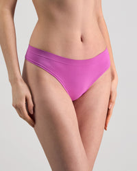 Model wears Seamless Soft Thong in RADIANT ORCHID. On body side view