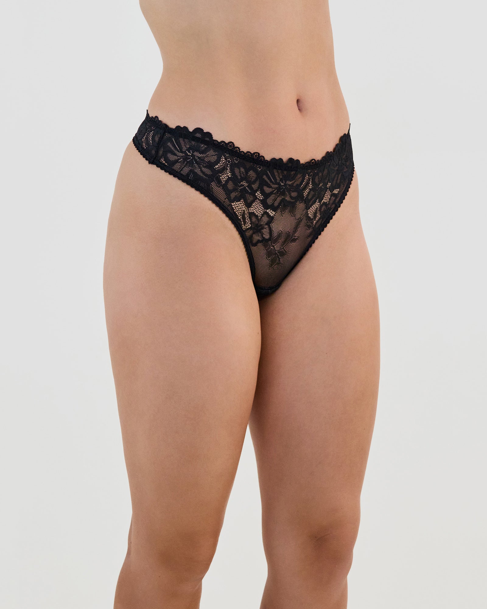Model wears All Lacey Thong in BLACK. On body side view