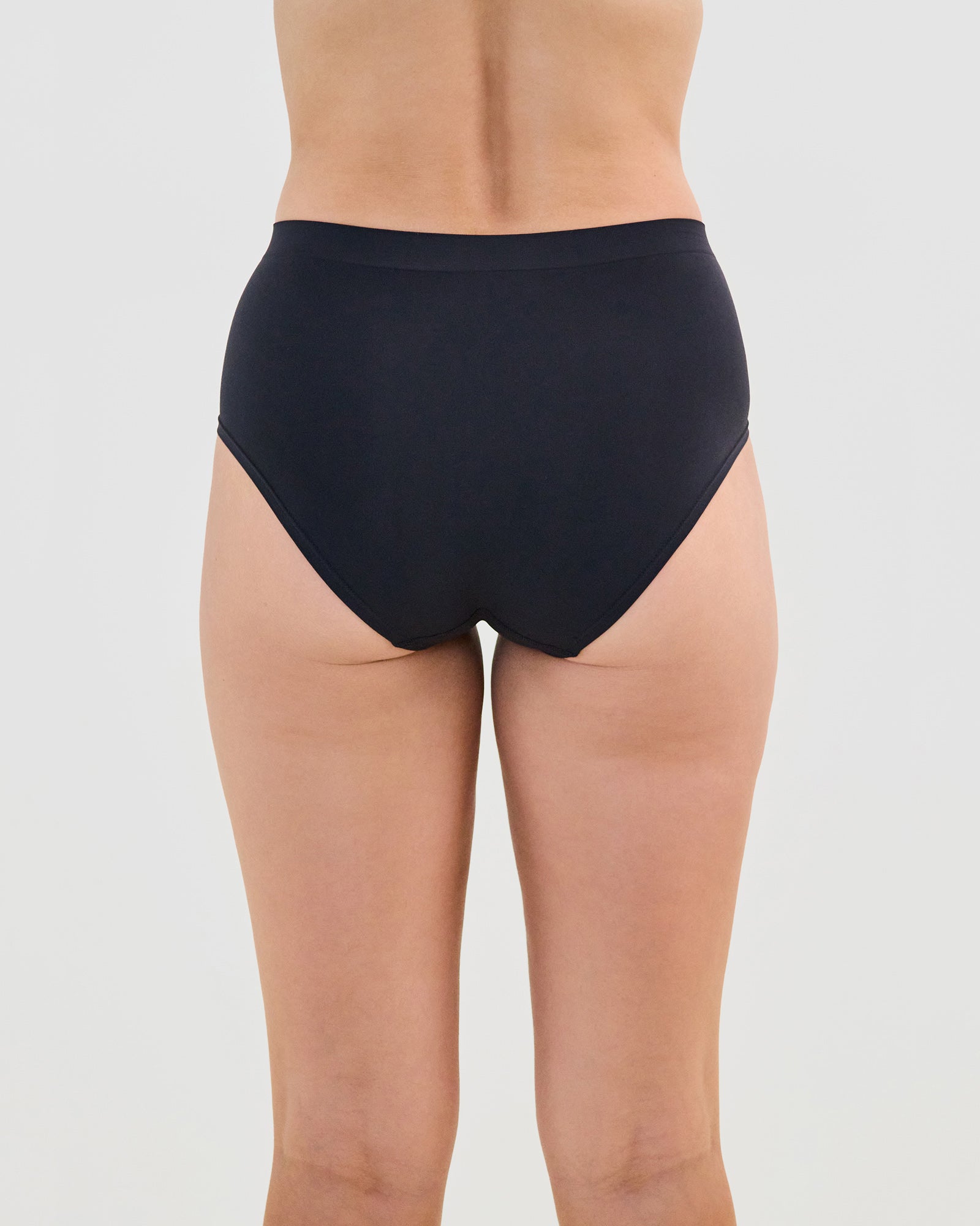Model wears Seamless Soft Full Brief in BLACK. On body back view
