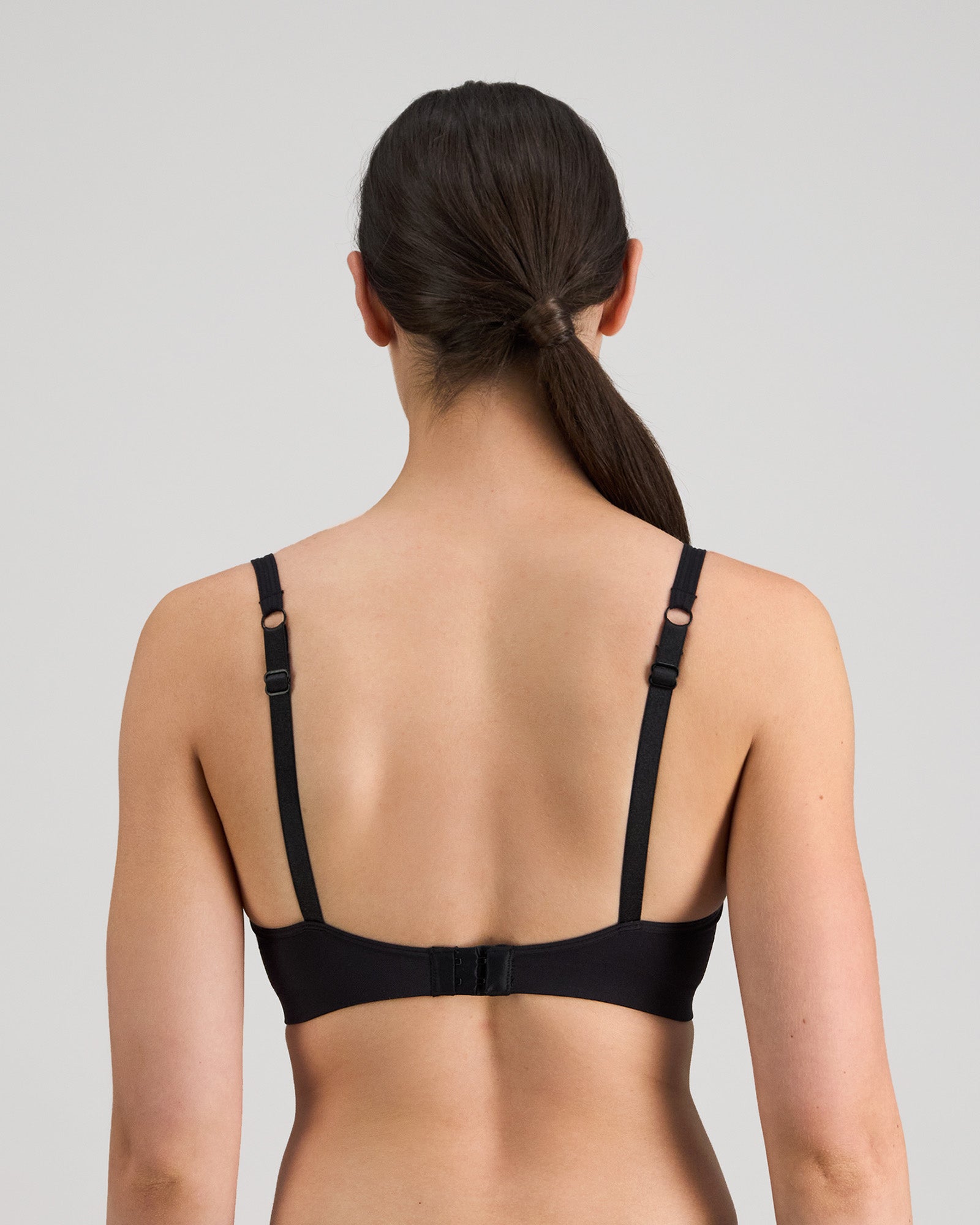 Model wears Simply Seamless Contour Bra in BLACK. On body back view