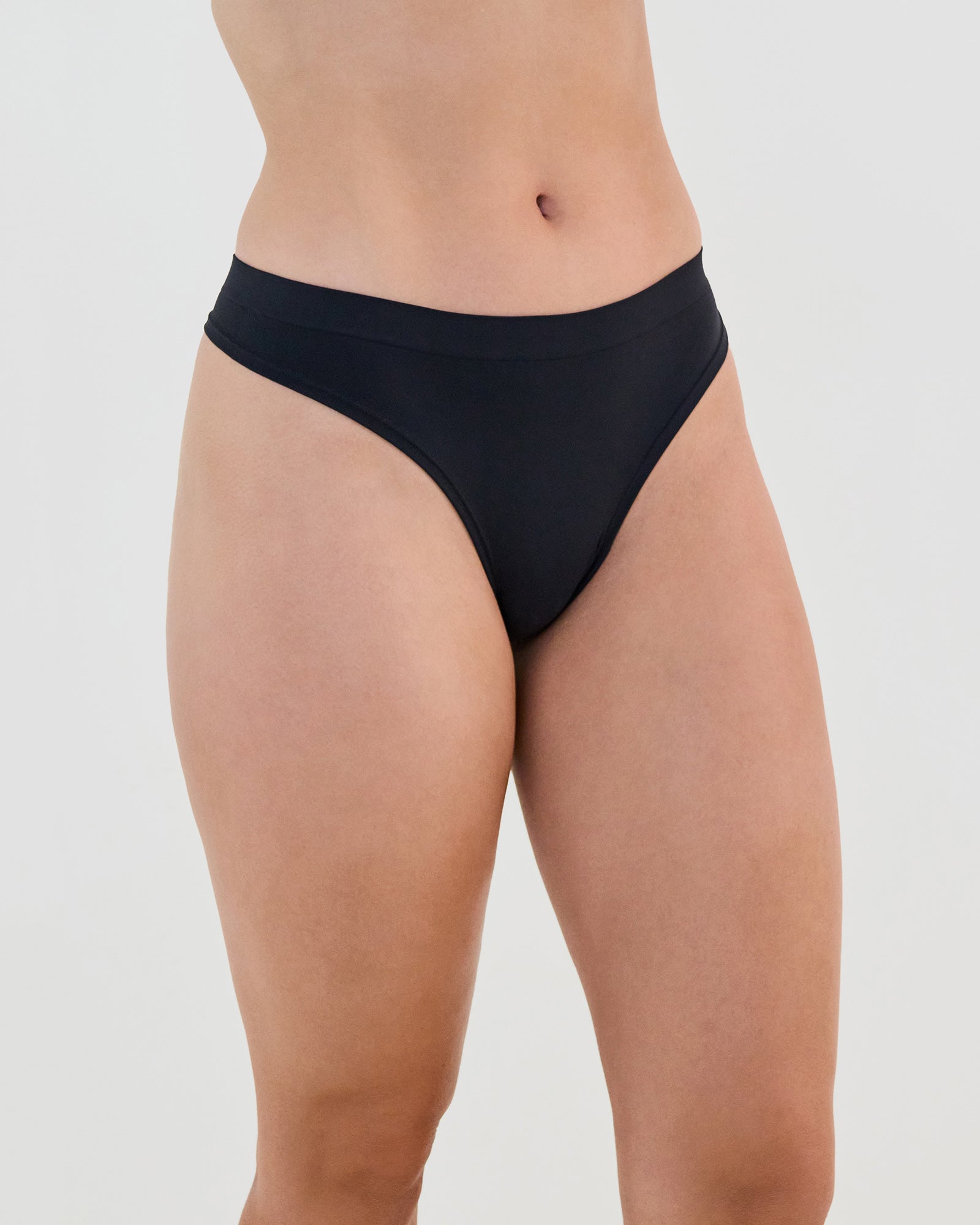 Model wears Seamless Soft Thong in BLACK. On body side view