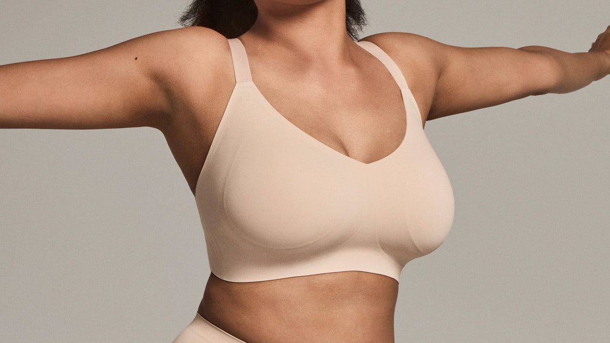 Woman wearing a beige bralette against a neutral background