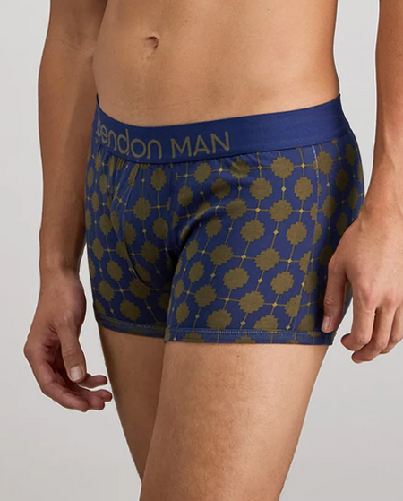 A close-up of a man wearing blue boxer briefs with a gold geometric pattern and a blue waistband that reads 'Bendon MAN'.