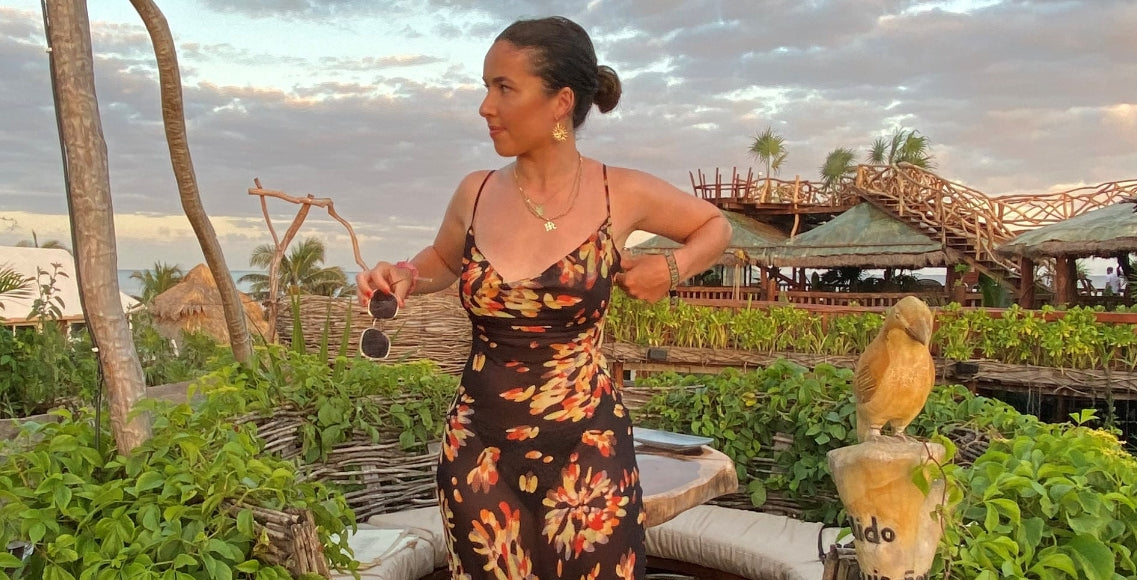 Woman in tropical country standing up wearing a black print dress with a strapless bra