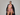 Woman wearing a pink lingerie set with sunglasses and a black coat on a gray background