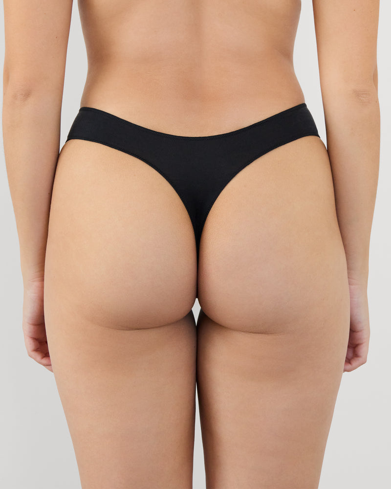 Model wears Au Naturel Thong in BLACK. On body back view