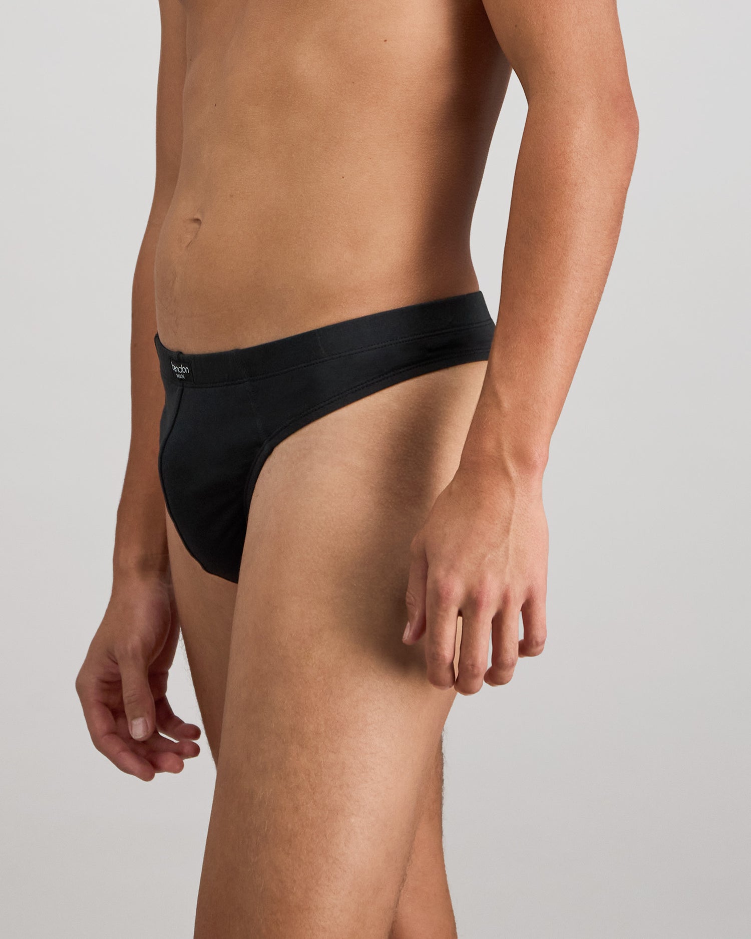 Model wears Cotton Stretch Mens Thong in BLACK. On body side view