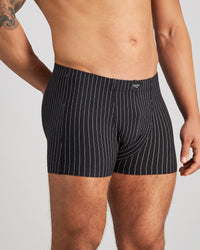 Model wears Cotton Stretch Mens Trunk in BLACK PINSTRIPE. On body side view