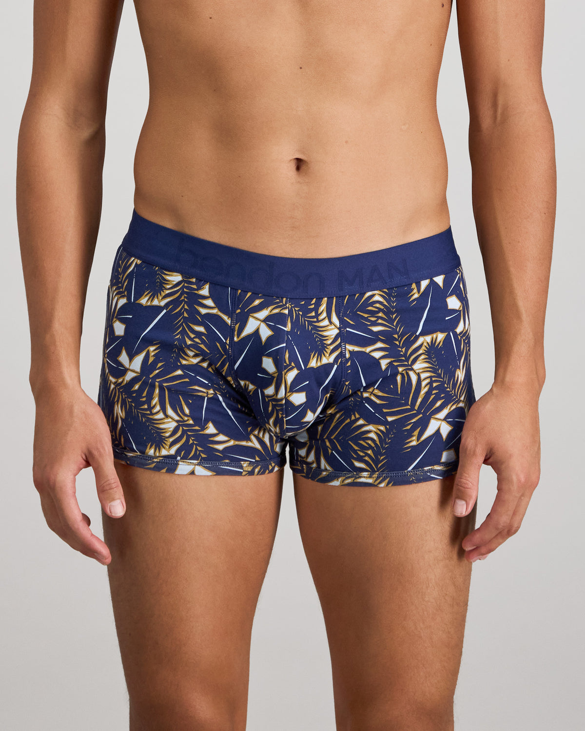 Model wears Retros Print Mens Trunk in GOLD TROPICAL PRINT. On body front view