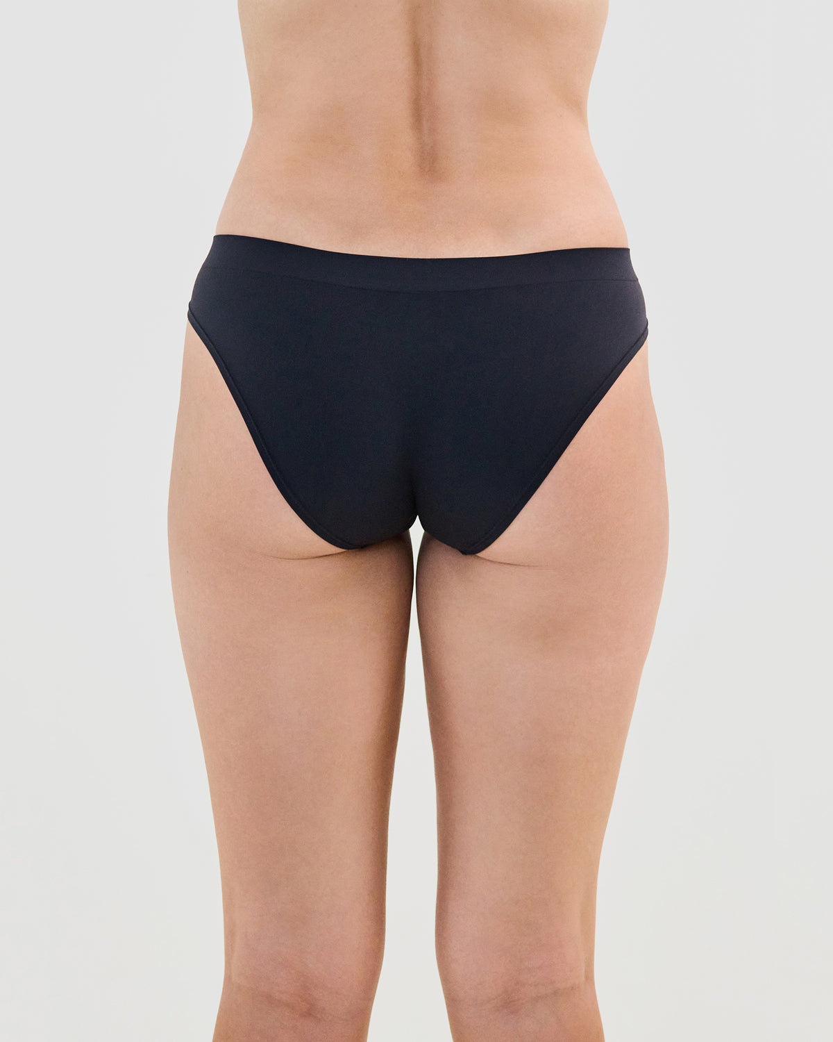 Model wears Seamless Soft Bikini in BLACK. On body back view