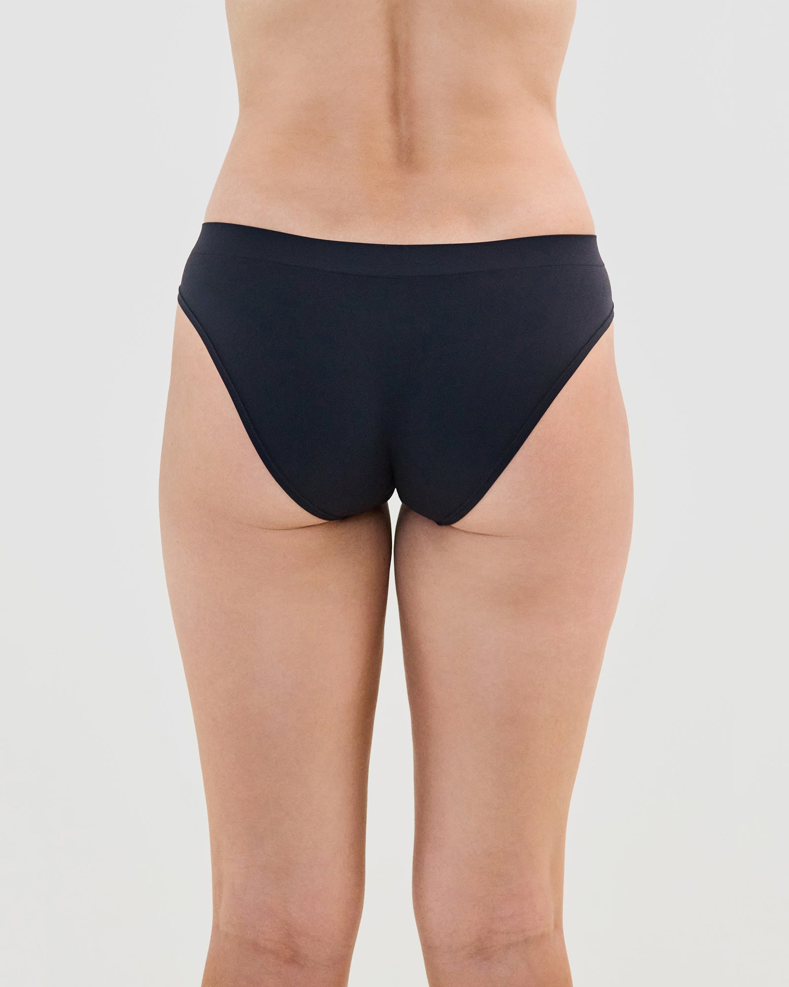 Model wears Seamless Soft Bikini in BLACK. On body back view