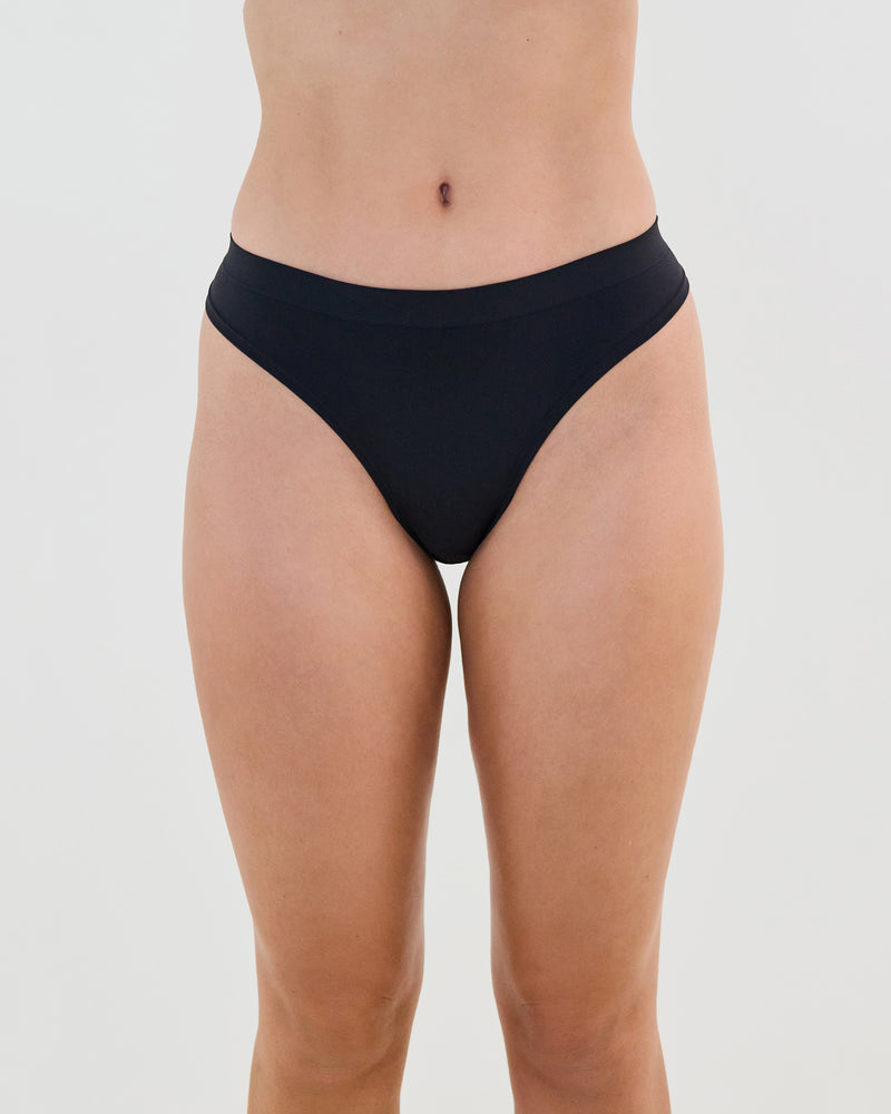 Model wears Seamless Soft Thong in BLACK. On body front view