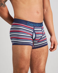 Model wears Bold Stripe Mens Trunk in PEACOAT/SALSA STRIPE. On body side view