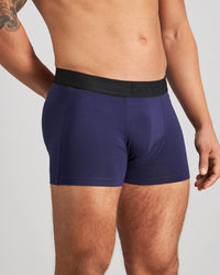 Model wears Everyday Essential Mens Trunk in PEACOAT. On body side view