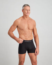 Model wears Cotton Classics Mens Trunk in BLACK. On body side view
