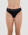 Model wears Cotton And Lace Thong in BLACK. On body front view