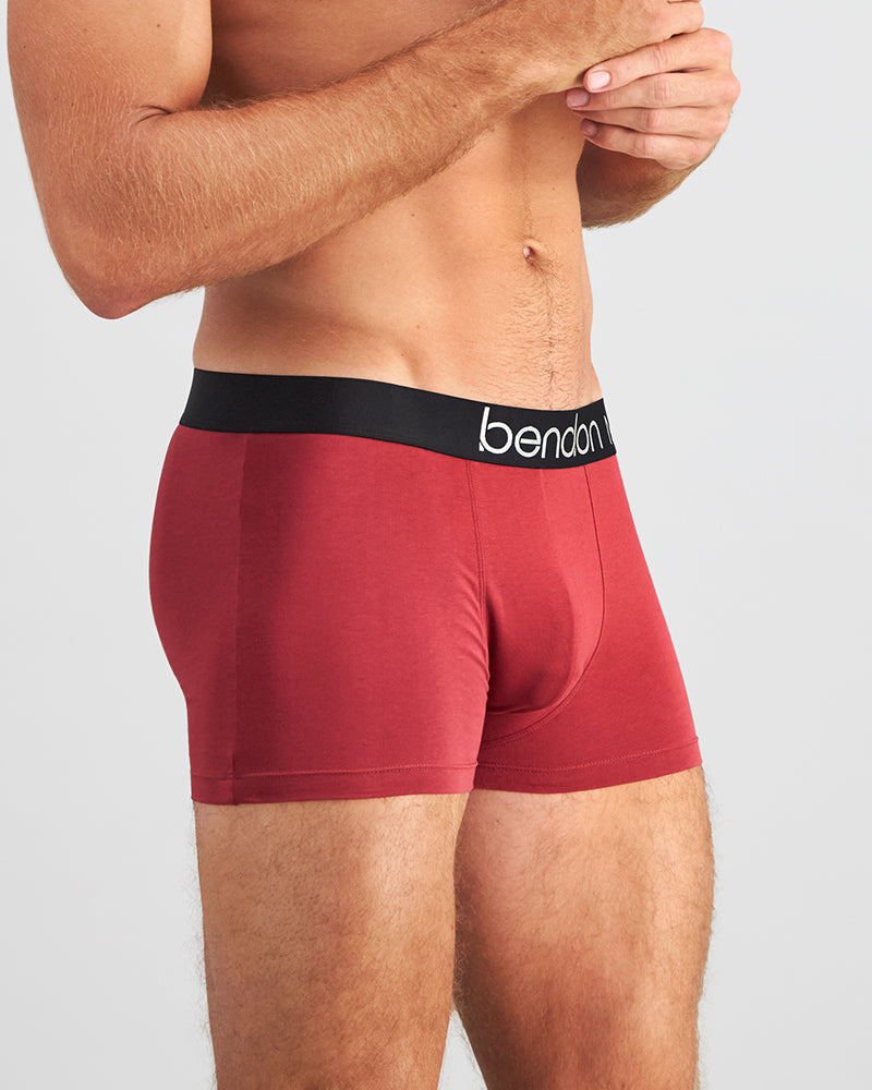 Model wears Everyday Essential Mens Trunk in TIBETAN RED. On body side view