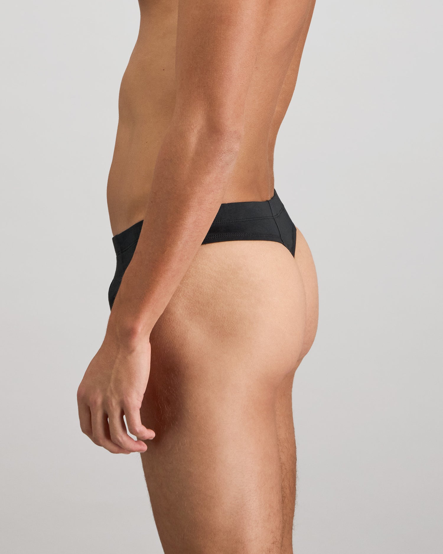 Model wears Cotton Stretch Mens Thong in BLACK. On body back view