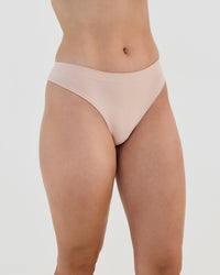 Model wears Seamless Soft Thong in LATTE. On body side view