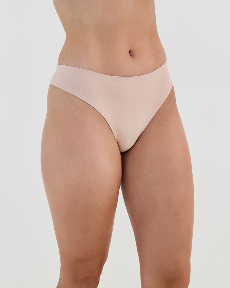 Model wears Seamless Soft Thong in LATTE. On body side view