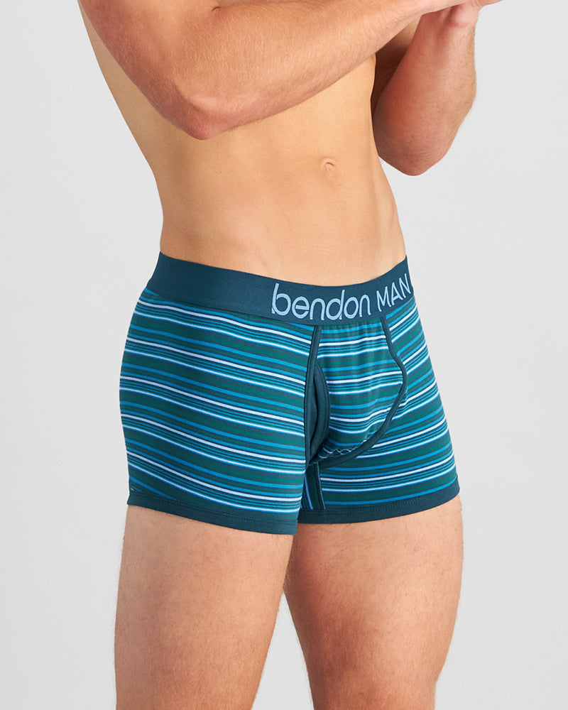 Model wears Bold Stripe Mens Trunk in DEEP TEAL/DEEP LAKE. On body side view