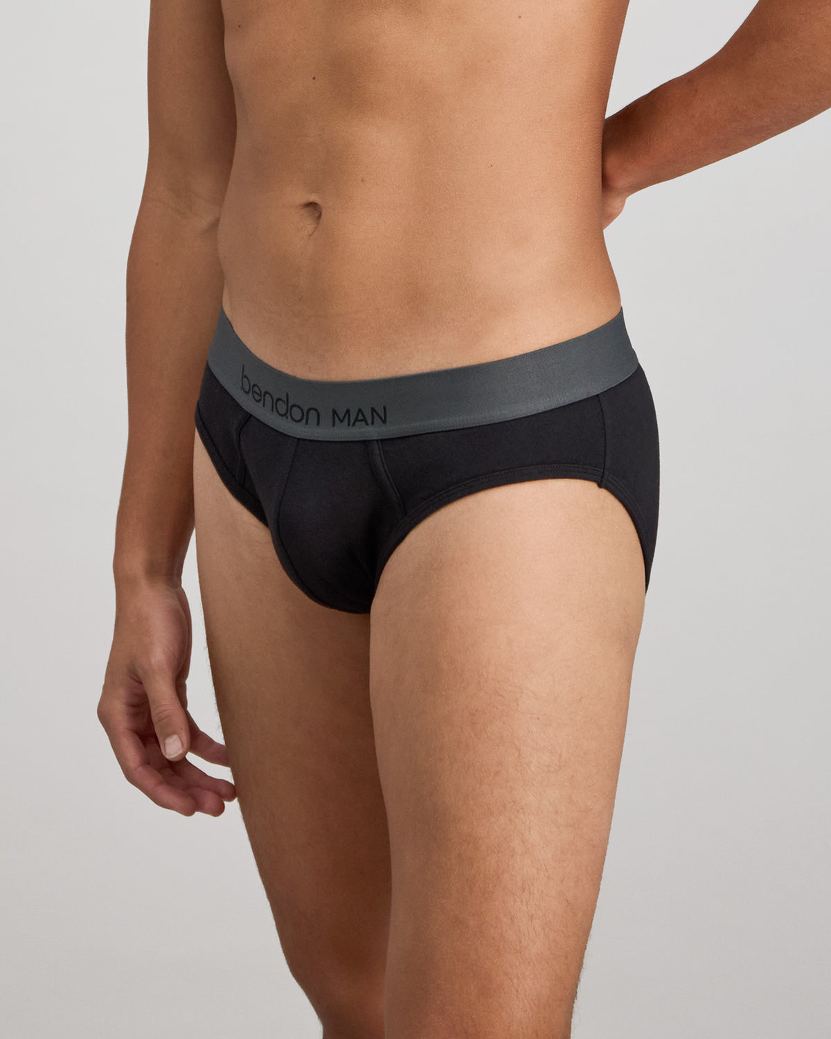 Model wears Cotton Low-Rise Mens Brief in BLACK. On body side view