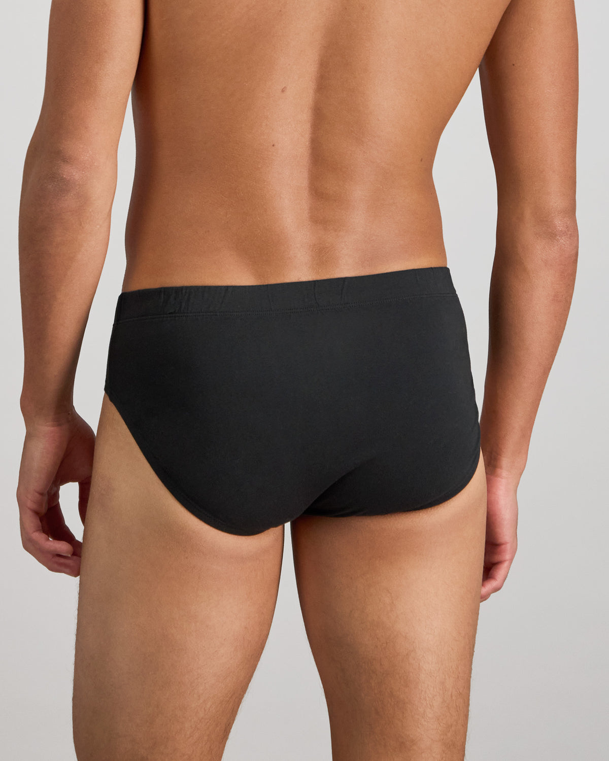 Model wears Cotton Stretch Mens Brief in BLACK. On body back view