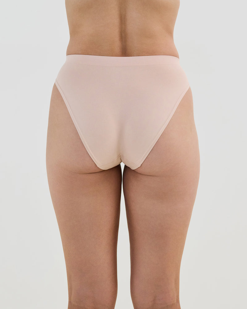 Model wears Seamless Soft High Cut Brief in LATTE. On body back view