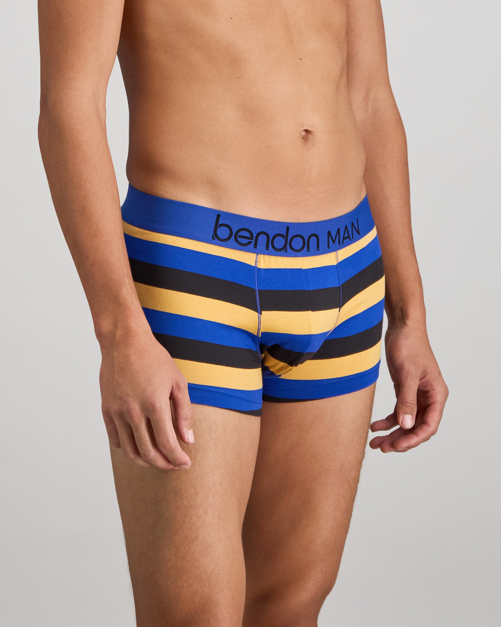 Model wears Rugby Stripe Mens Trunk in BLACK/SURF/OAK BUFF. On body side view