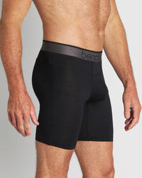 Model wears Everyday Active Mens Long Trunk in BLACK. On body side view
