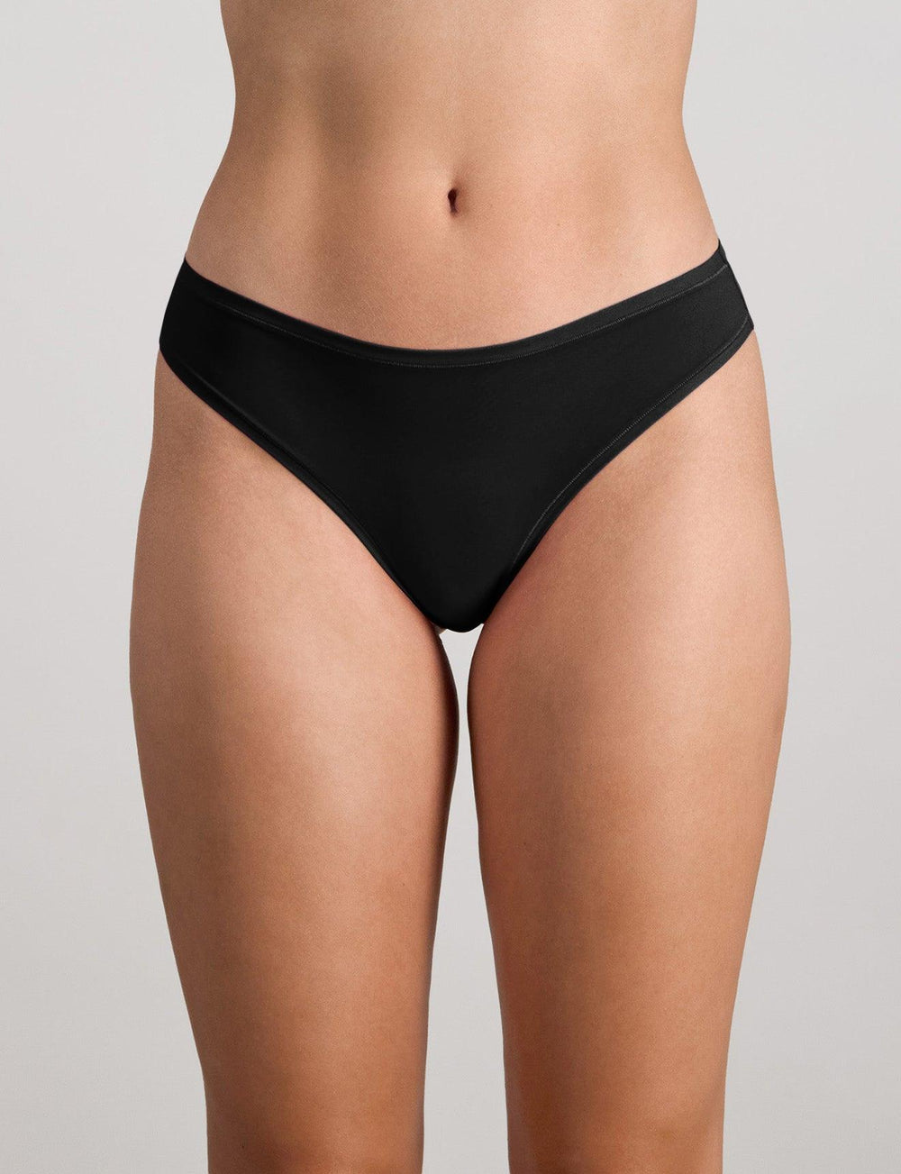 Model wears Extra-Ordinary Thong in BLACK. On body front view