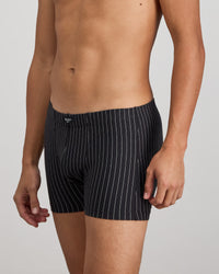 Model wears Cotton Stretch Mens Trunk in BLACK PINSTRIPE. On body side view