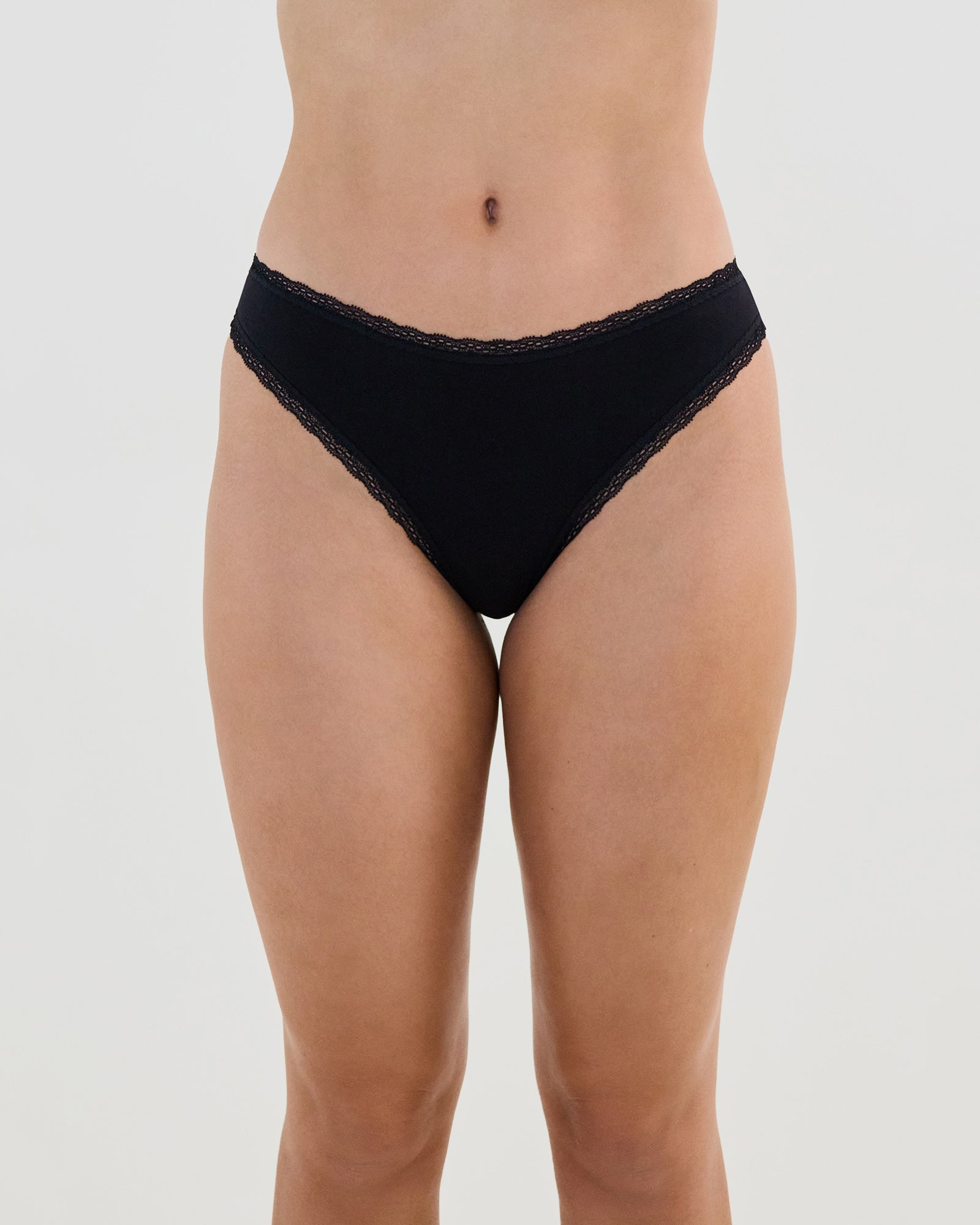 Model wears Stretch Cotton Thong in BLACK. On body front view