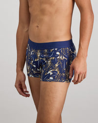 Model wears Retros Print Mens Trunk in GOLD TROPICAL PRINT. On body side view