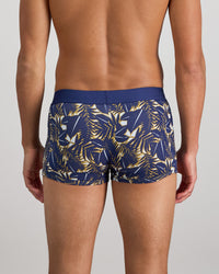 Model wears Retros Print Mens Trunk in GOLD TROPICAL PRINT. On body back view