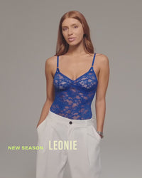 model-poses-wearing-blue-lacey-bodysuit-and-white-trouser