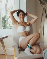model poses on chair wearing body cocoon white cotton lingerie set