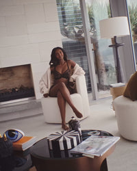 model poses in lounge wearing black romilly underwire bra and thong