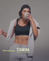 model-holds-two-coffees-posing-in-black-sports-bra