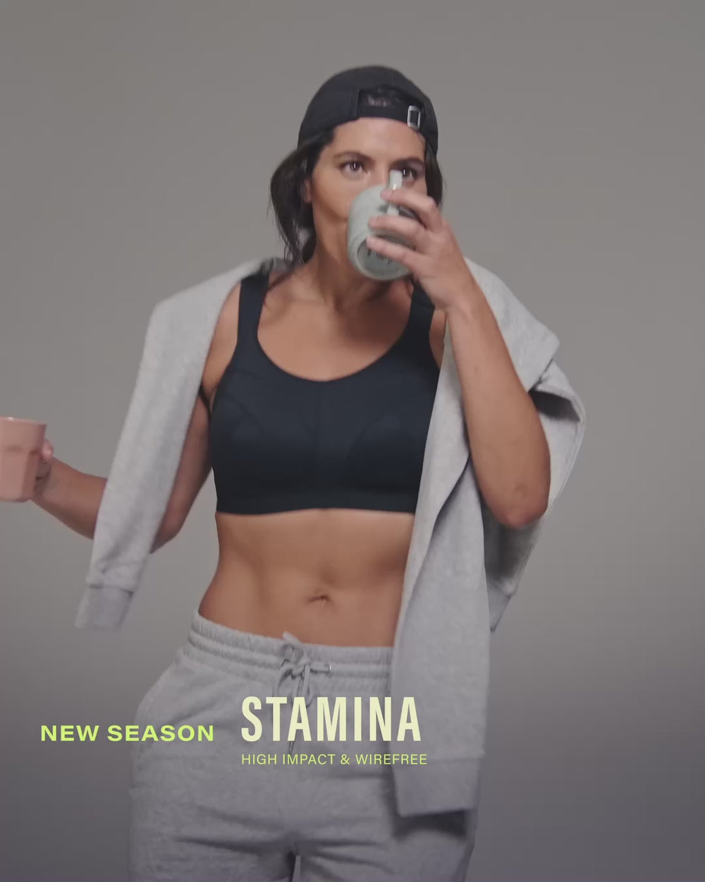 model-holds-two-coffees-posing-in-black-sports-bra