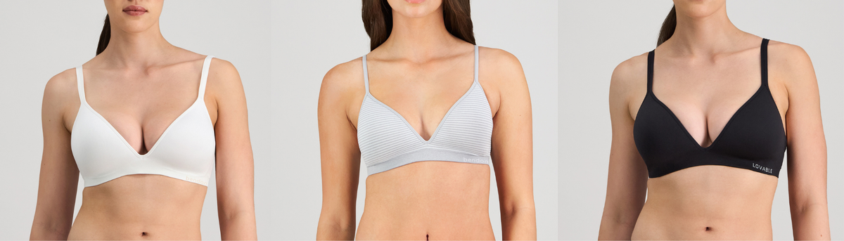 Three women wearing different colored bras on a plain background