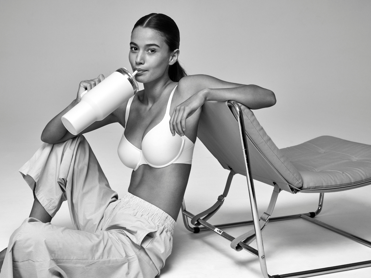 Woman in a white bikini sitting on a modern chair with a white background